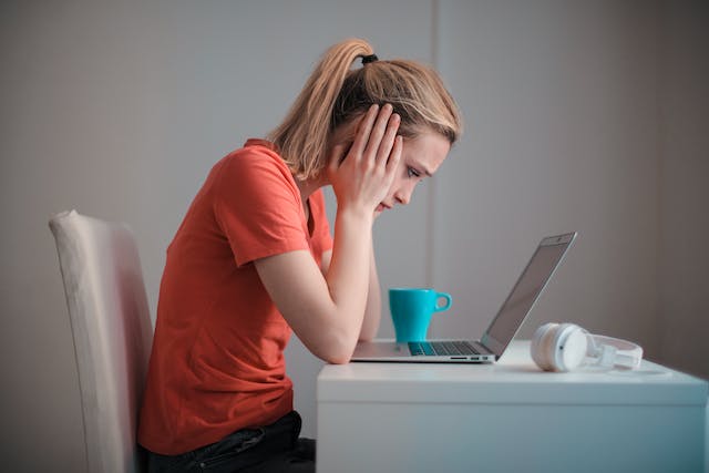 A person at their laptop looking stressed.
