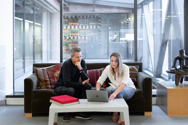 Two property managers sitting next to each other on a couch working on a laptop in front of them