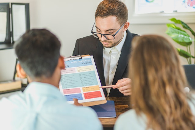 Property manager showing a document to two people sitting across a desk