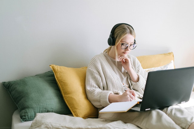 Person wearing headphones using their laptop on a couch