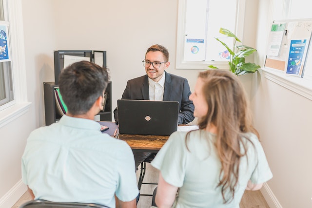 Property manager working on their laptop behind a desk, two people are sitting across from them