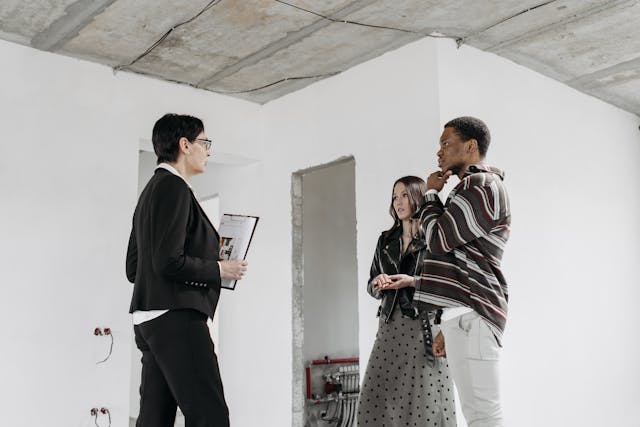 A landlord speaking with two tenants in an empty room.