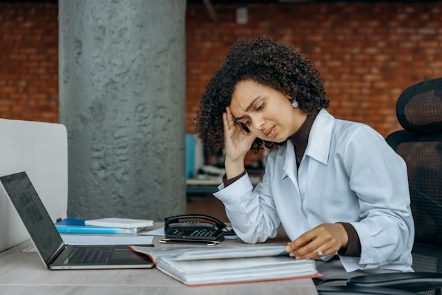 A person at their laptop looking stressed.