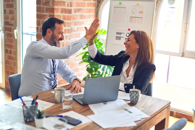 Two people in business attire high-fiving